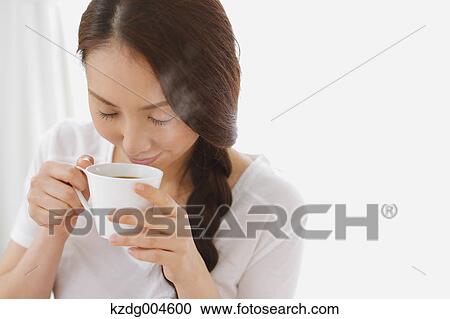 Stock Image - Young attractive Japanese woman having cofee at home. Fotosearch