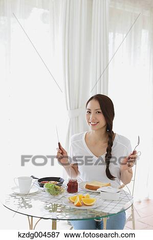 Stock Photo - Young attractive Japanese woman having breakfast at home. Fotosearch