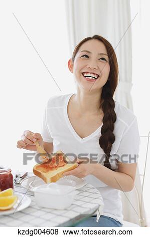 Stock Photo - Young attractive Japanese woman having breakfast at home. Fotosearch