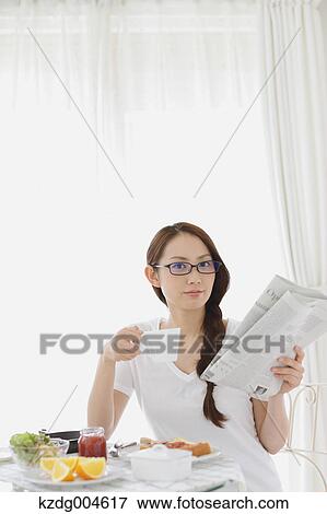 Stock Photo - Young attractive Japanese woman having breakfast at home. Fotosearch