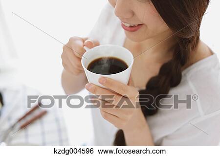 Stock Photograph - Young attractive Japanese woman having cofee at home. Fotosearch