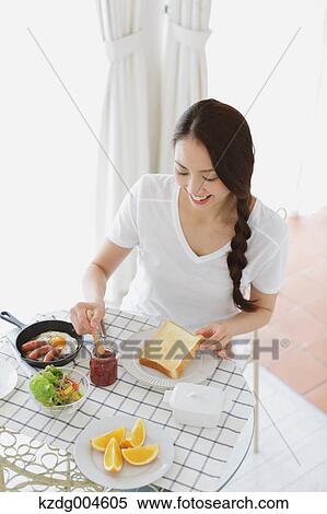 Stock Photography - Young attractive Japanese woman having breakfast at home. Fotosearch