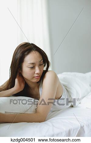 Stock Image - Young attractive Japanese woman in bed. Fotosearch