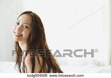 Stock Photograph - Young attractive Japanese woman in bed. Fotosearch