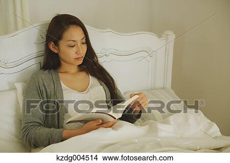 Young attractive Japanese woman reading in bed View Large Photo Image Picture - Young attractive Japanese woman reading in bed. Fotosearch