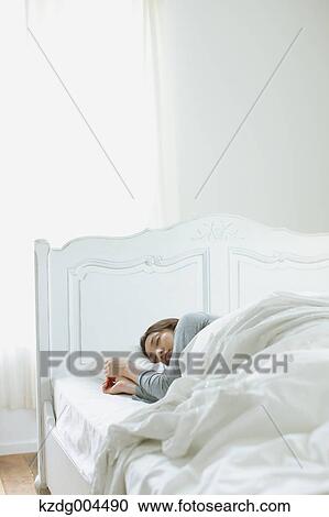 Stock Image - Young attractive Japanese woman sleeping in bed. Fotosearch