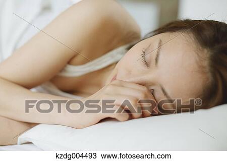 Stock Image - Young attractive Japanese woman sleeping in bed. Fotosearch