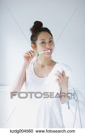 Stock Image - Young attractive Japanese woman brushing teeth in the bathroom. Fotosearch