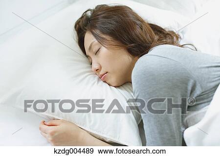 Stock Photo - Young attractive Japanese woman sleeping in bed. Fotosearch