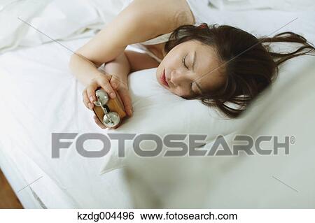 Stock Photograph - Young attractive Japanese woman sleeping in bed. Fotosearch