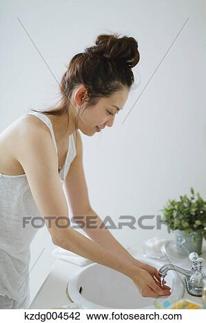 Stock Image - Young attractive Japanese woman washing face in the bathroom. Fotosearch