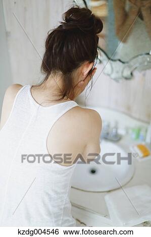 Stock Photograph - Young attractive Japanese woman washing face in the bathroom. Fotosearch