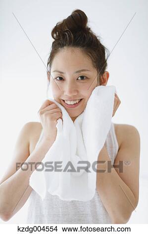 Young attractive Japanese woman wiping face with towel in the bathroom View Large Photo Image Picture - Young attractive Japanese woman wiping face with towel in the bathroom. Fotosearch