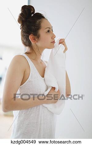 Stock Photo - Young attractive Japanese woman wiping face with towel in the bathroom. Fotosearch