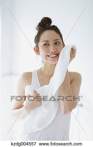 Stock Photo - Young attractive Japanese woman wiping face with towel in the bathroom. Fotosearch