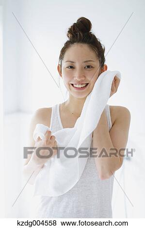 Stock Photo - Young attractive Japanese woman wiping face with towel in the bathroom. Fotosearch