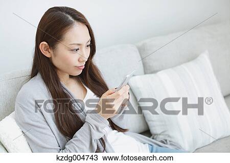 Young attractive Japanese woman with smartphone on the sofa View Large Photo Image Stock Image - Young attractive Japanese woman with smartphone on the sofa. Fotosearch