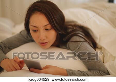 Young attractive Japanese woman with smartphone in bed View Large Photo Image Stock Photo - Young attractive Japanese woman with smartphone in bed. Fotosearch