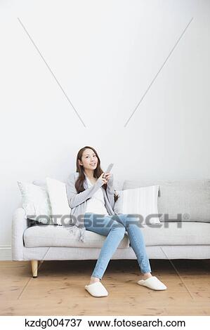 Young attractive Japanese woman with smartphone on the sofa View Large Photo Image Stock Photo - Young attractive Japanese woman with smartphone on the sofa. Fotosearch