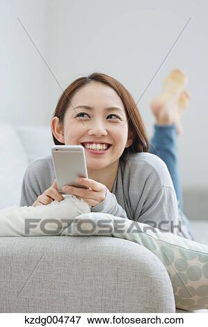 Young attractive Japanese woman with smartphone on the sofa View Large Photo Image Stock Photo - Young attractive Japanese woman with smartphone on the sofa. Fotosearch