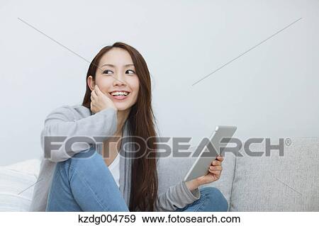 Young attractive Japanese woman with tablet on the sofa View Large Photo Image Stock Photo - Young attractive Japanese woman with tablet on the sofa. Fotosearch