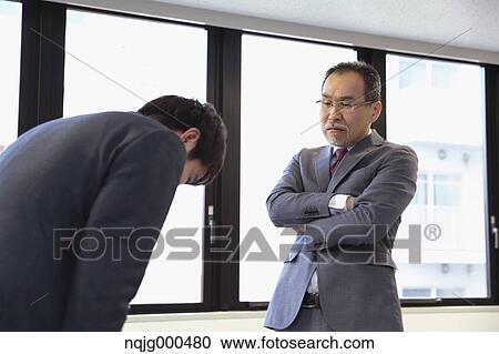 Stock Image - Young Japanese businessman being scored by his boss. Fotosearch