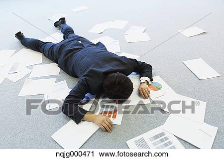 Stock Image - Young Japanese businessman with lots of scattered documents. Fotosearch