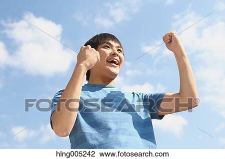 Young Japanese man cheering against blue sky View Large Photo Image Stock Image - Young Japanese man cheering against blue sky. Fotosearch