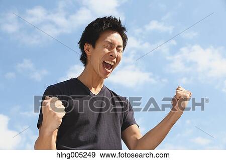 Young Japanese man cheering against blue sky View Large Photo Image Stock Photo - Young Japanese man cheering against blue sky. Fotosearch