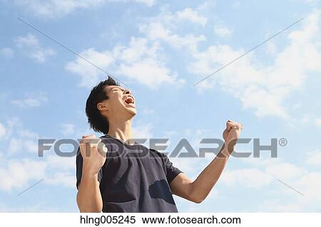 Young Japanese man cheering against blue sky View Large Photo Image Stock Photography - Young Japanese man cheering against blue sky. Fotosearch