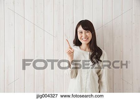 Stock Photo - Young Japanese woman against wooden wall. Fotosearch