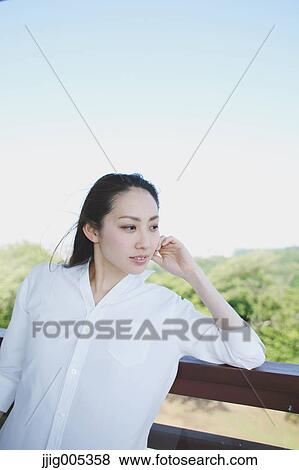Stock Photo - Young Japanese woman at observation deck in a city park. Fotosearch