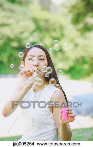 Young Japanese woman blowing soap bubbles in a city park View Large Photo Image Picture - Young Japanese woman blowing soap bubbles in a city park. Fotosearch
