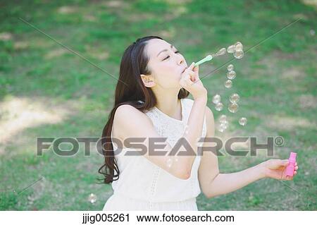Young Japanese woman blowing soap bubbles in a city park View Large Photo Image Stock Image - Young Japanese woman blowing soap bubbles in a city park. Fotosearch