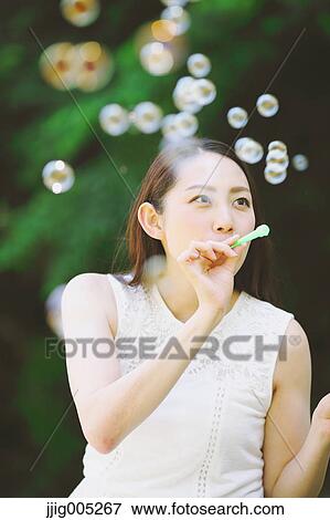 Young Japanese woman blowing soap bubbles in a city park View Large Photo Image Stock Photo - Young Japanese woman blowing soap bubbles in a city park. Fotosearch