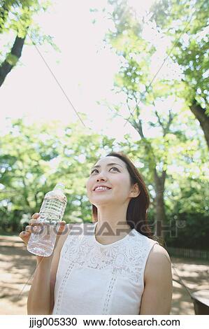 Young Japanese woman drinking water in a city park View Large Photo Image Stock Image - Young Japanese woman drinking water in a city park. Fotosearch