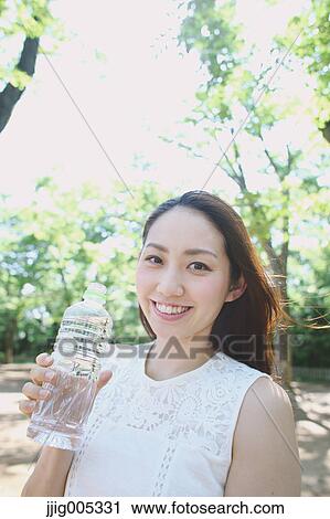 Young Japanese woman drinking water in a city park View Large Photo Image Stock Image - Young Japanese woman drinking water in a city park. Fotosearch