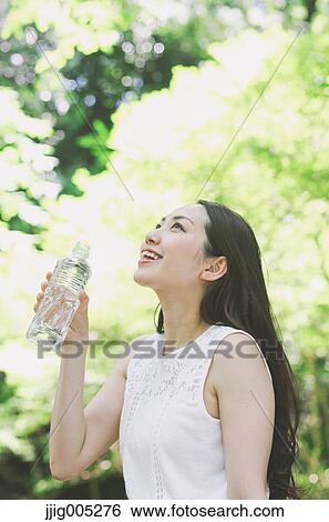 Young Japanese woman drinking water in a city park View Large Photo Image Stock Photograph - Young Japanese woman drinking water in a city park. Fotosearch