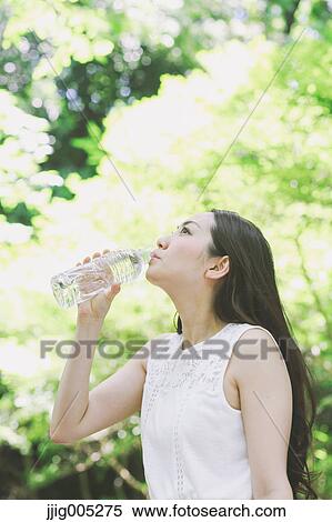 Young Japanese woman drinking water in a city park View Large Photo Image Stock Photography - Young Japanese woman drinking water in a city park. Fotosearch