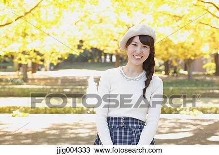 Stock Image - Young Japanese woman in a city park. Fotosearch