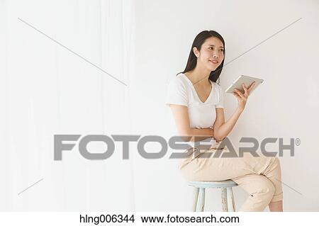 Young Japanese woman on a chair in a white room View Large Photo Image Picture - Young Japanese woman on a chair in a white room. Fotosearch