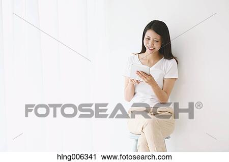 Young Japanese woman on a chair in a white room View Large Photo Image Stock Image - Young Japanese woman on a chair in a white room. Fotosearch