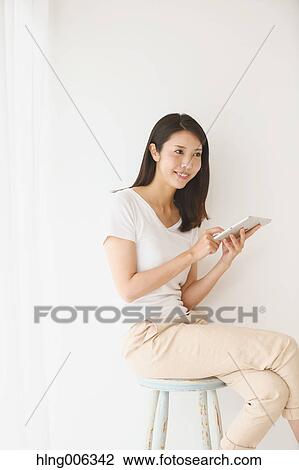 Young Japanese woman on a chair in a white room View Large Photo Image Stock Image - Young Japanese woman on a chair in a white room. Fotosearch