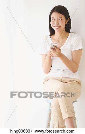 Young Japanese woman on a chair in a white room View Large Photo Image Stock Photo - Young Japanese woman on a chair in a white room. Fotosearch