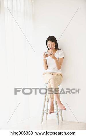 Young Japanese woman on a chair in a white room View Large Photo Image Stock Photo - Young Japanese woman on a chair in a white room. Fotosearch