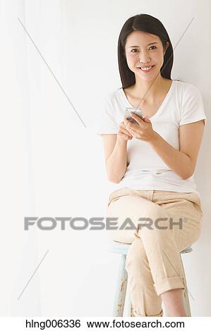 Young Japanese woman on a chair in a white room View Large Photo Image Stock Photograph - Young Japanese woman on a chair in a white room. Fotosearch