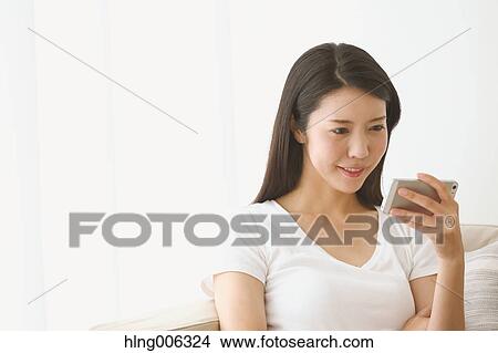 Picture - Young Japanese woman on the sofa in a white room. Fotosearch