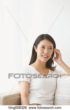 Stock Photograph - Young Japanese woman on the sofa in a white room. Fotosearch