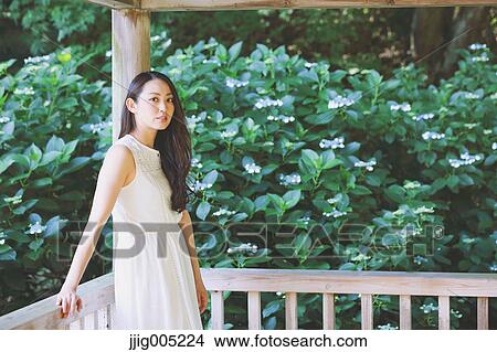 Young Japanese woman on wooden deck in a city park View Large Photo Image Picture - Young Japanese woman on wooden deck in a city park. Fotosearch