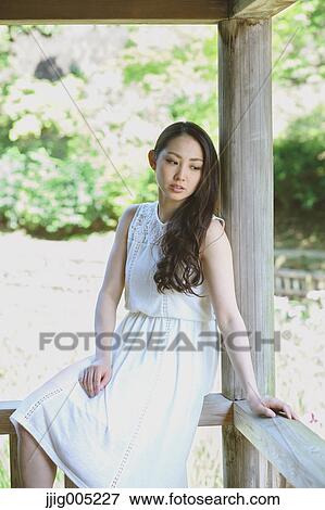 Stock Photo - Young Japanese woman on wooden deck in a city park. Fotosearch
